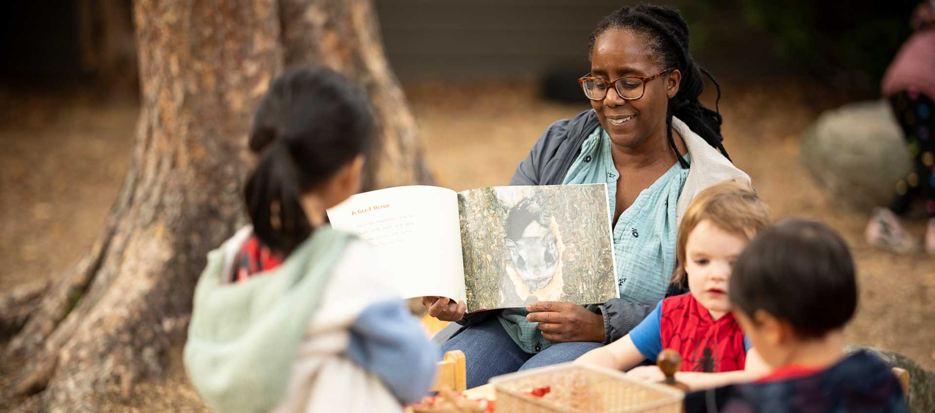 Pre-k teacher Nicole Siverls reads with students outdoors