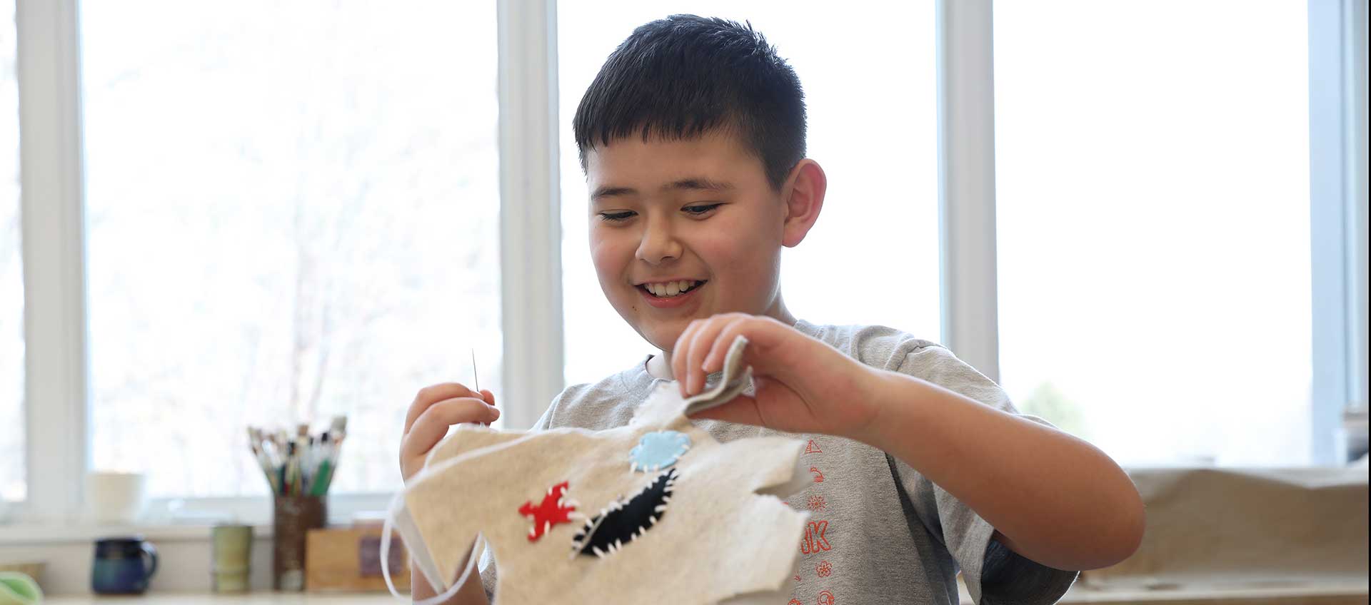 A student smiles while stitching a project in the art studio
