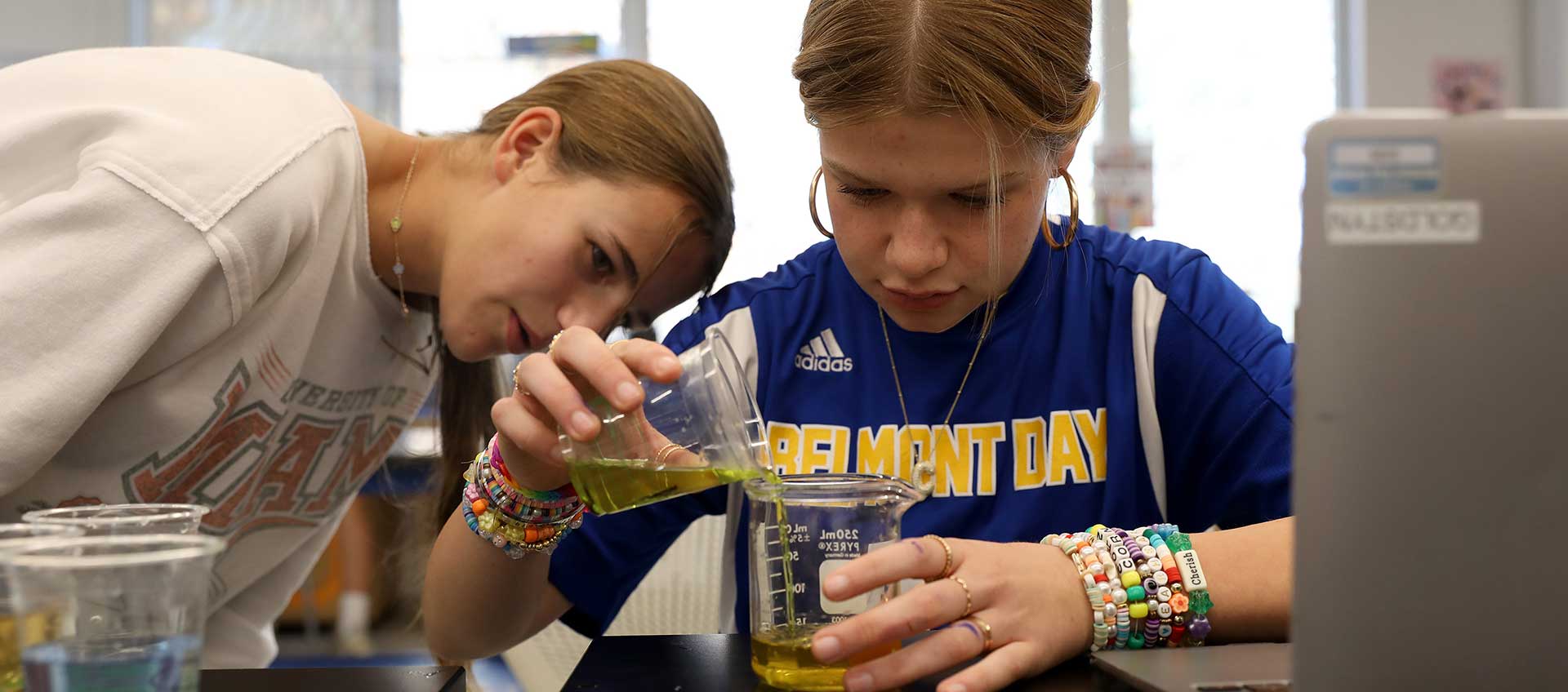 Two girls pour a liquid during a science lab