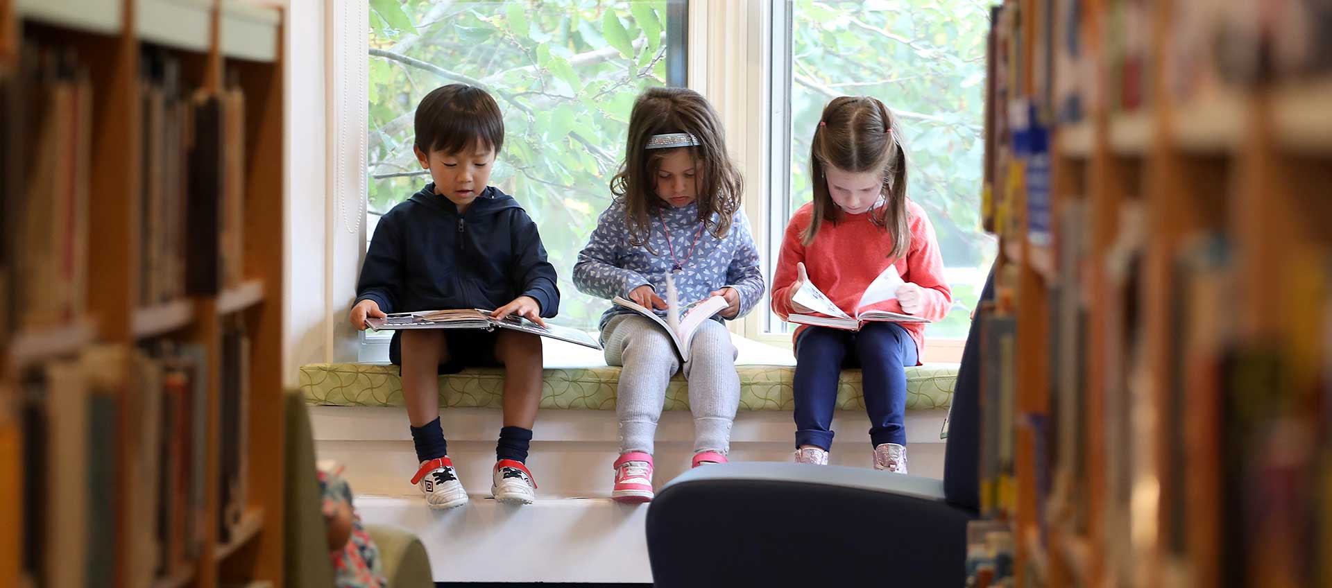 Three kindergartners read in the Erskine Library