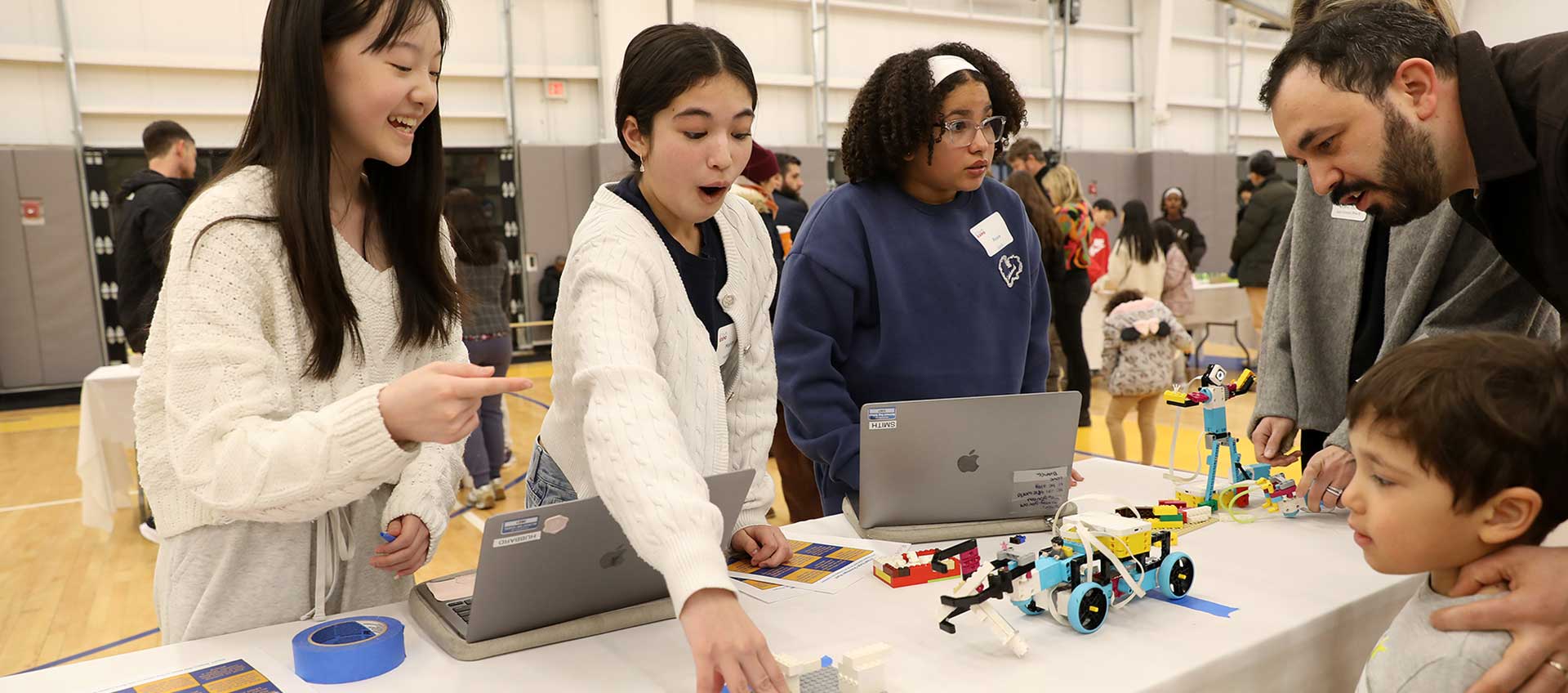 Three girls demonstrate their STEAM projects to a younger student and their parent