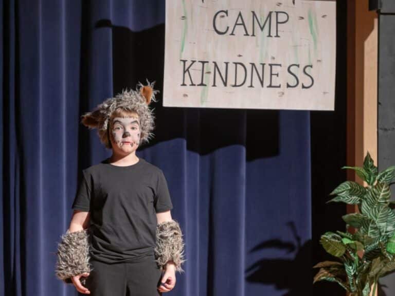 A young actor in costume on stage-First graders are introduced to performance skills through drama games, creative movement, and by performing alongside second graders as the chorus in a musical production.