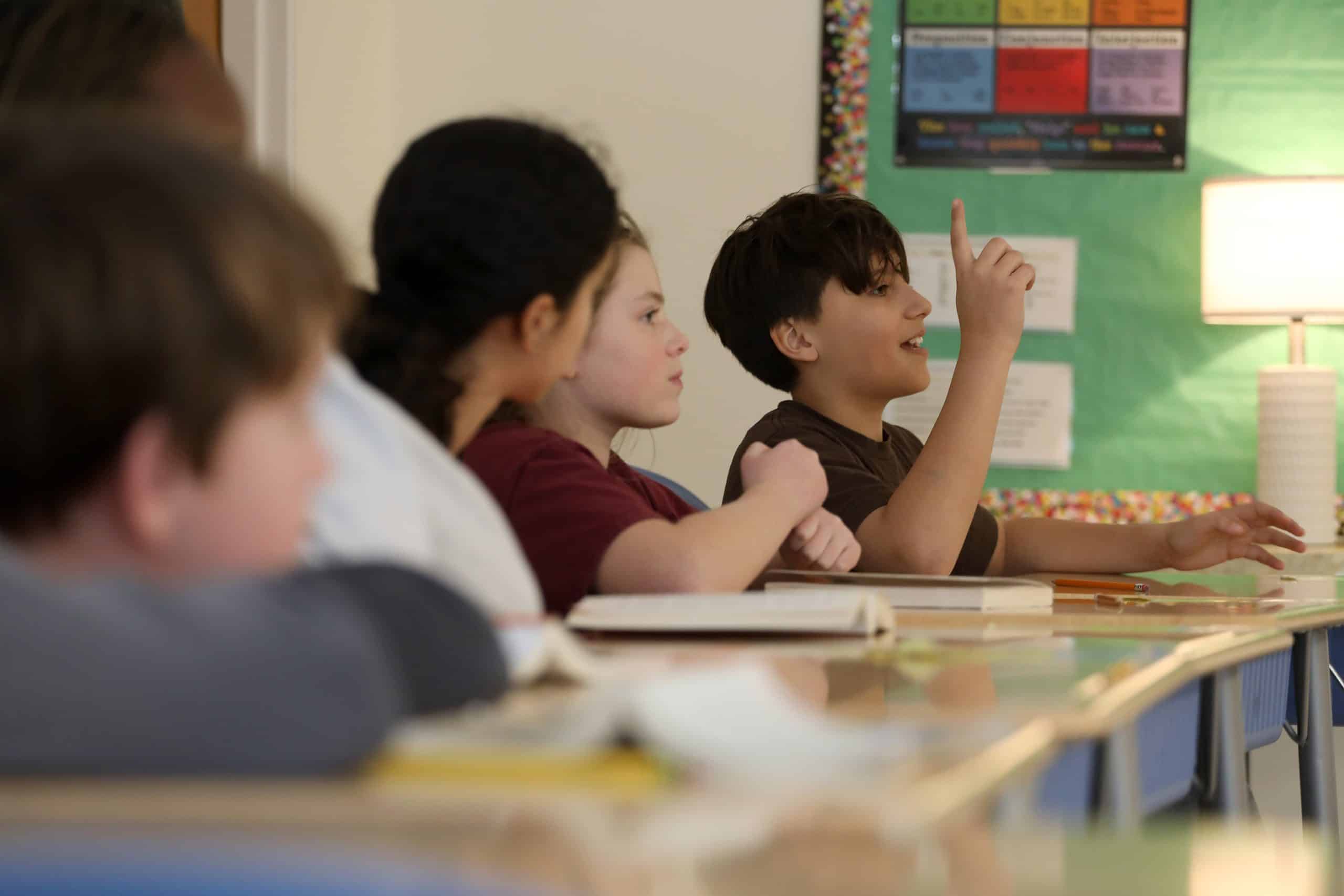 A student gestures at his desk in English class