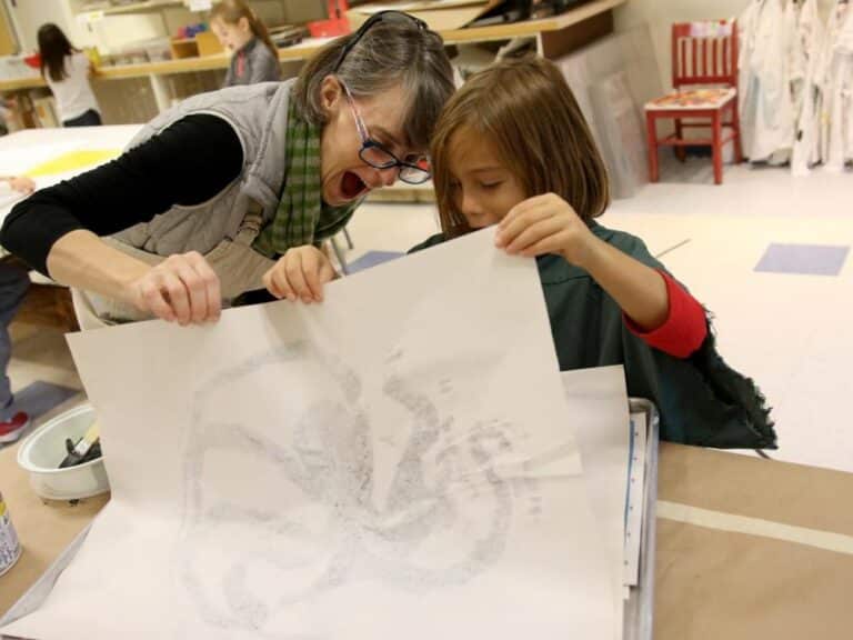 A teacher helps a student reveal his fish print