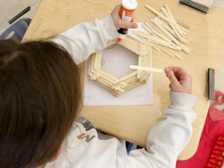 A second grader constructs a model for a woodworking project