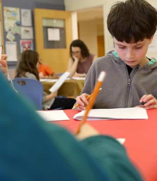 A boy works on a math problem at his desk