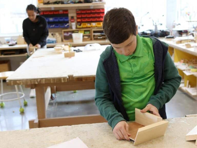 Two students in the woodworking studio sanding projects