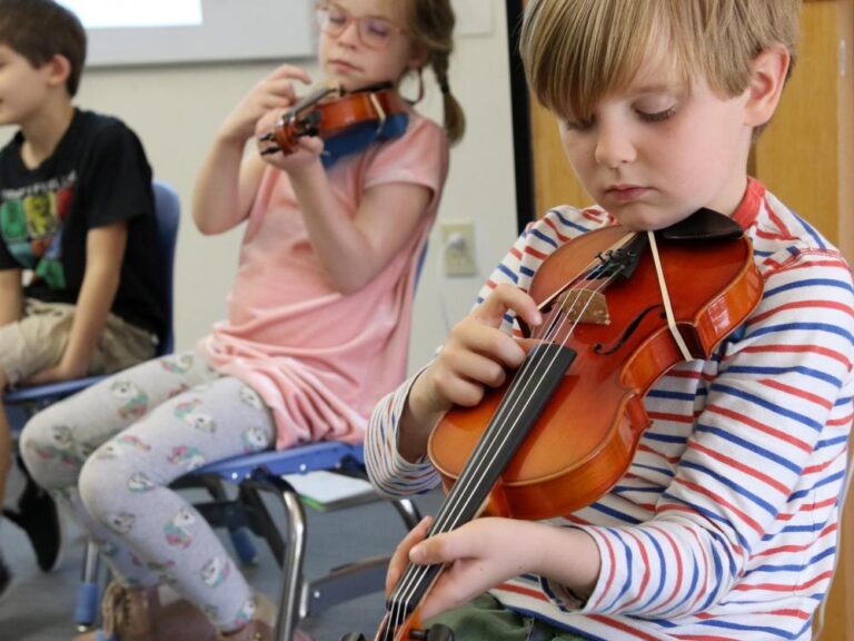 Two students and their violins in music class