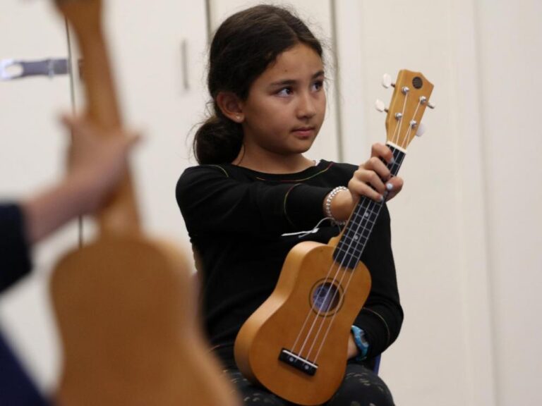 A girl holds her ukulele in music class
