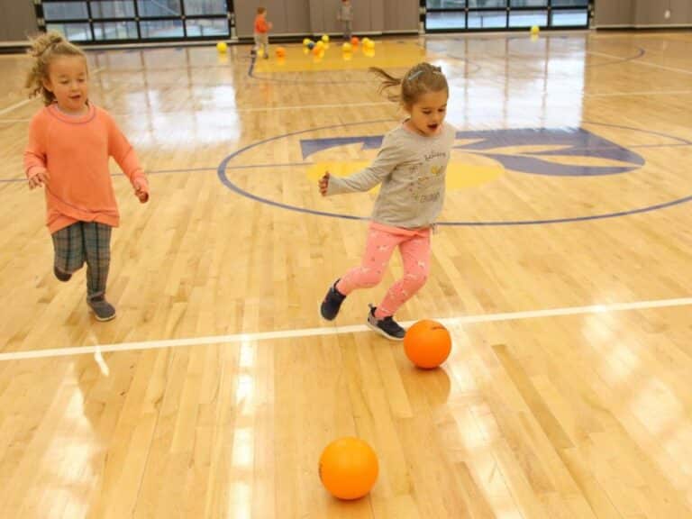 Two girls play soccer in the gym