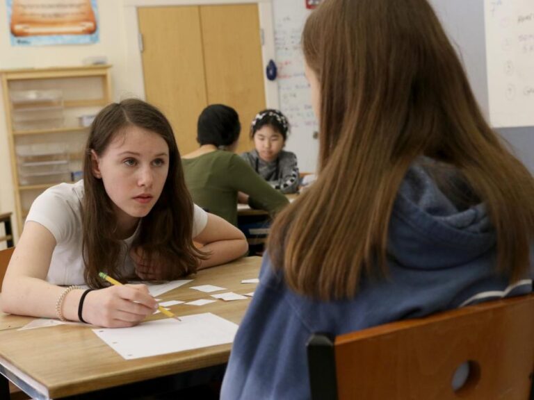 Two girls work together at their desks