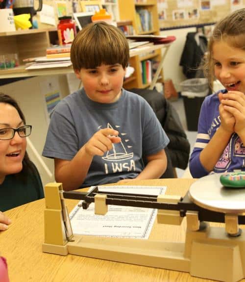 Two students share their math work with a teacher