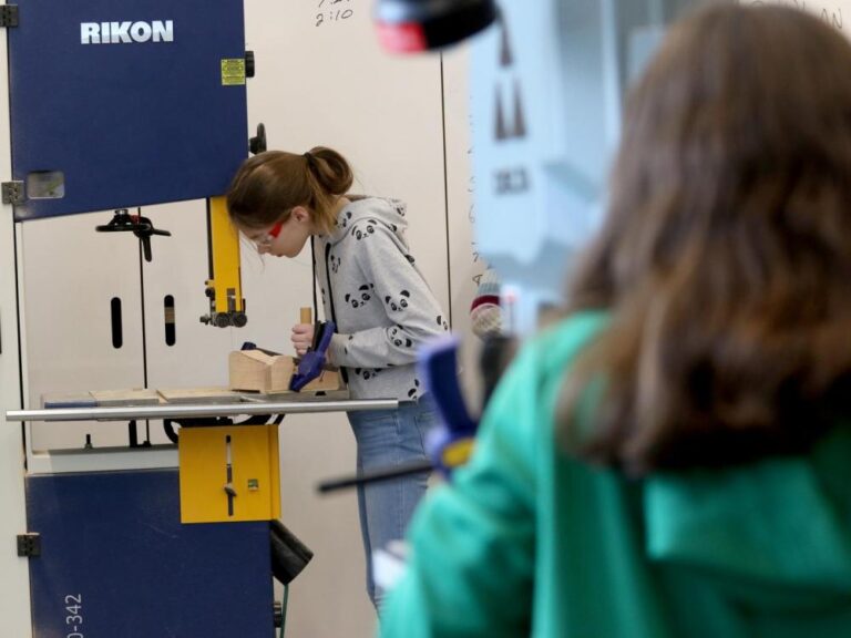 A student uses the drill press in the woodworking studio