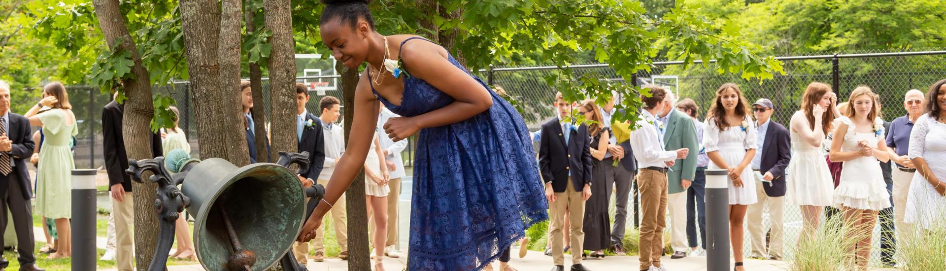 A student rings the BDS bell at the conclusion of graduation