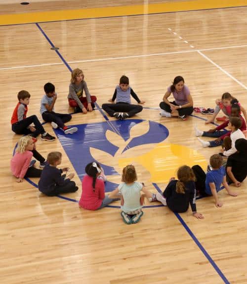 Students form a circle in the Barn gym with their teacher