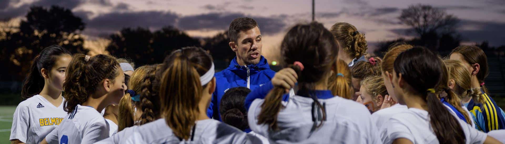 A coach discusses game strategy with soccer players