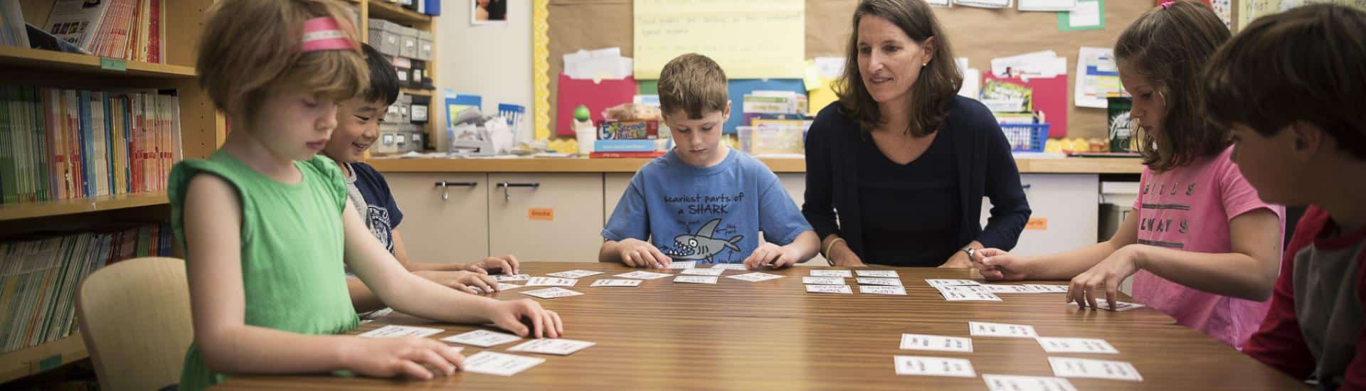 Teacher at table with young students