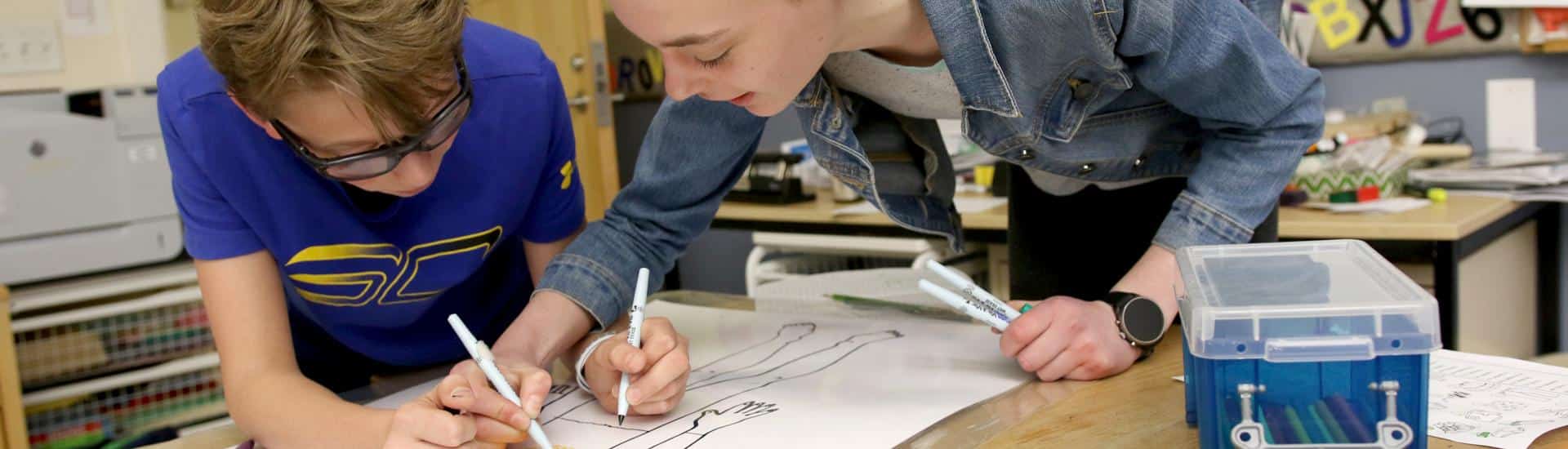 Two students work on a poster for Spanish class