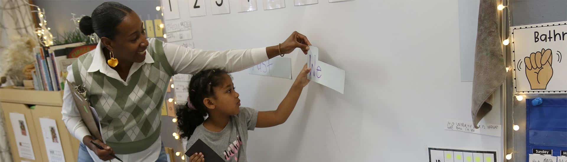 Associate teacher with a student at the white board during morning meeting