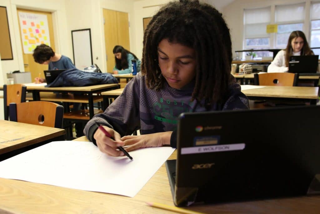A student writes at his desk in class