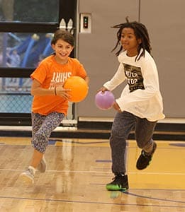 Two students playing basketball in the gym