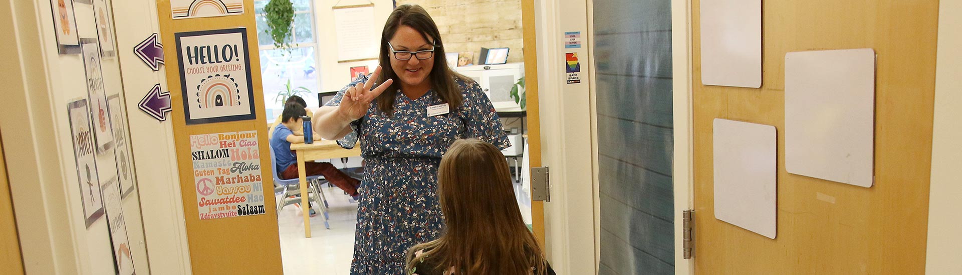 A teacher welcomes a student to class with a high five