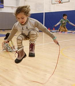 A first grade jumps rope in the gym