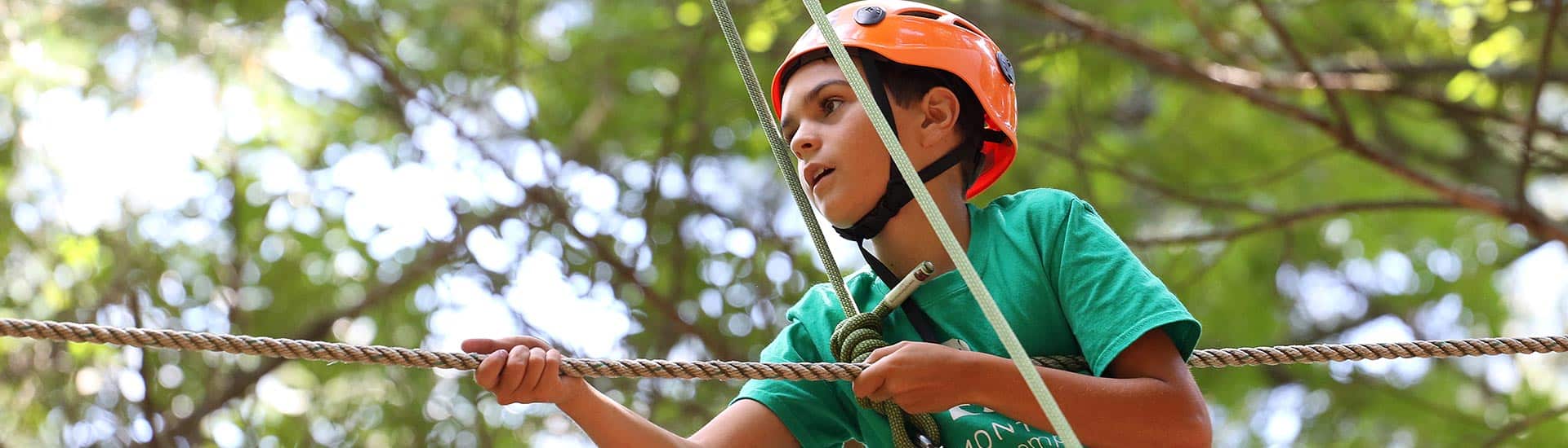 A camper navigates a high ropes course