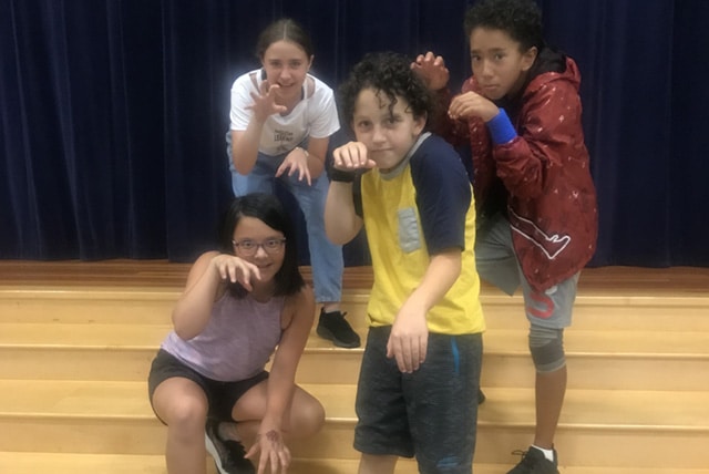 Four students demonstrate their character portraits in theater arts class