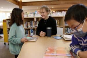 Alumna Isabel Moore works with two fourth grade students