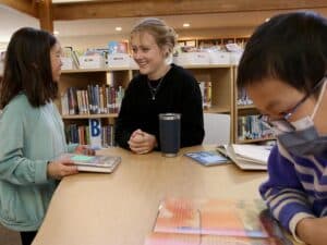 Alumna Isabel Moore works with two fourth graders in the Erskine Library