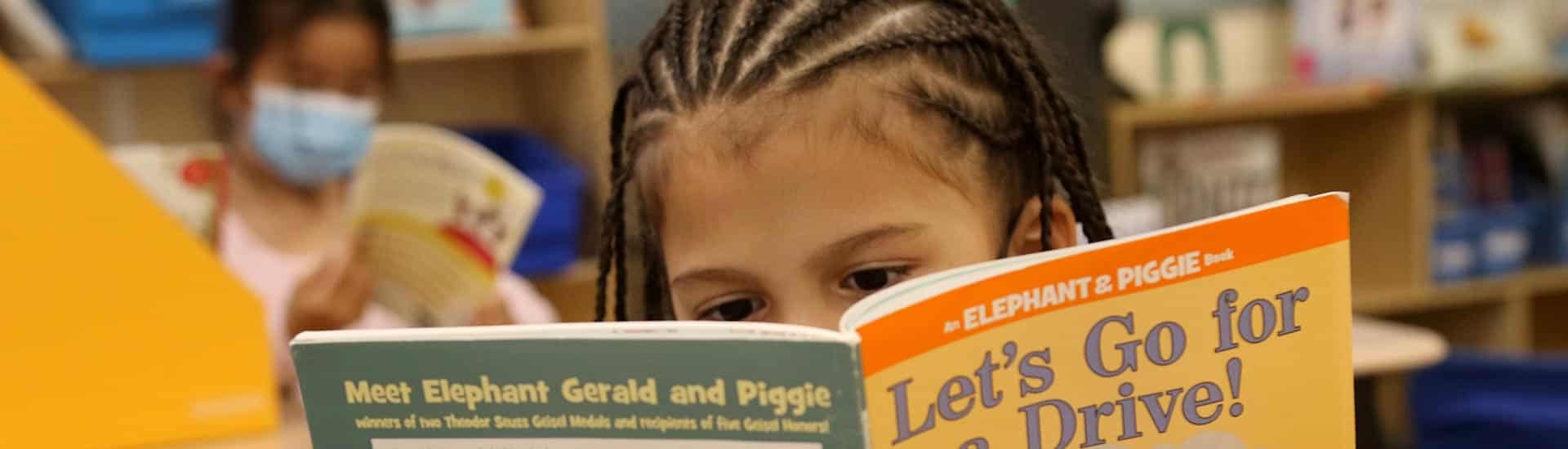 A student behind an Elephant and Piggie book