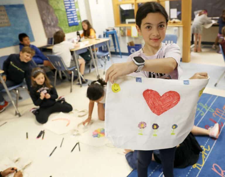A student shows the heart design on a tote bag she designed on community service day