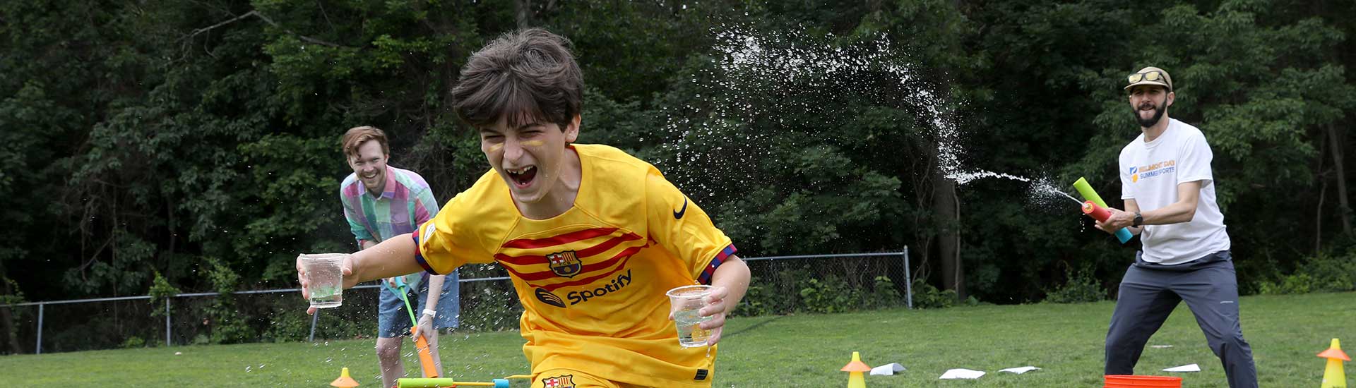 A student races past teachers with water squirters on Field Day