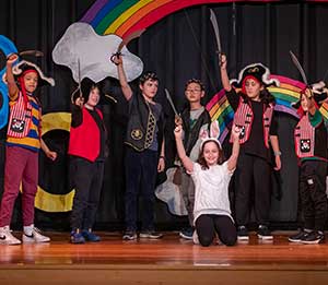 Fourth graders hold swords while singing the closing number of their class play