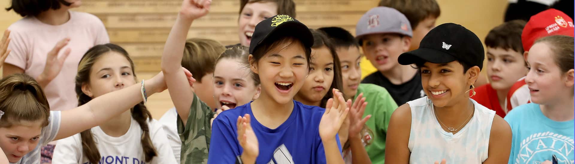 A group of students laugh and applaud at a sharing assembly