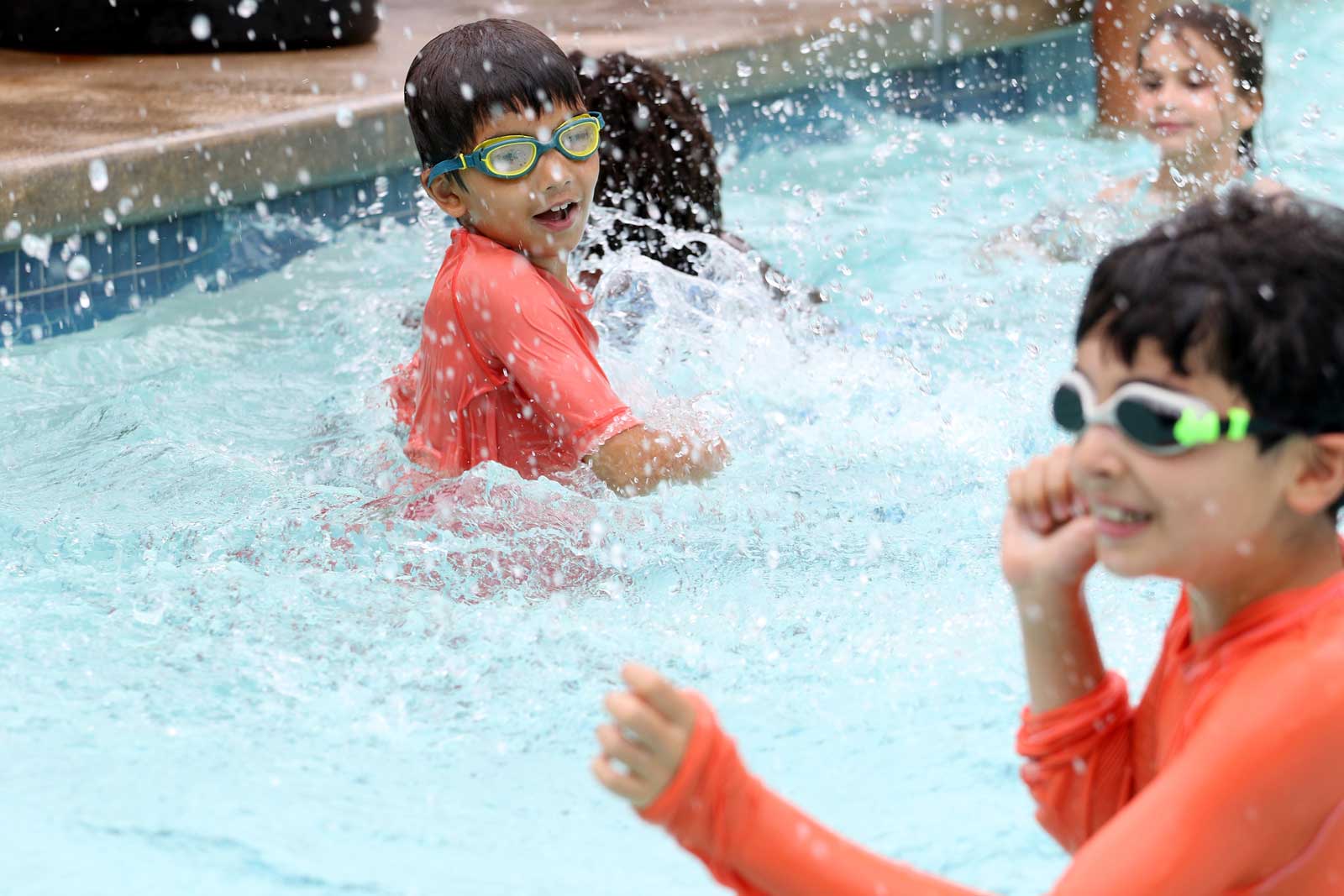 Swimmers smile and splash in the pool