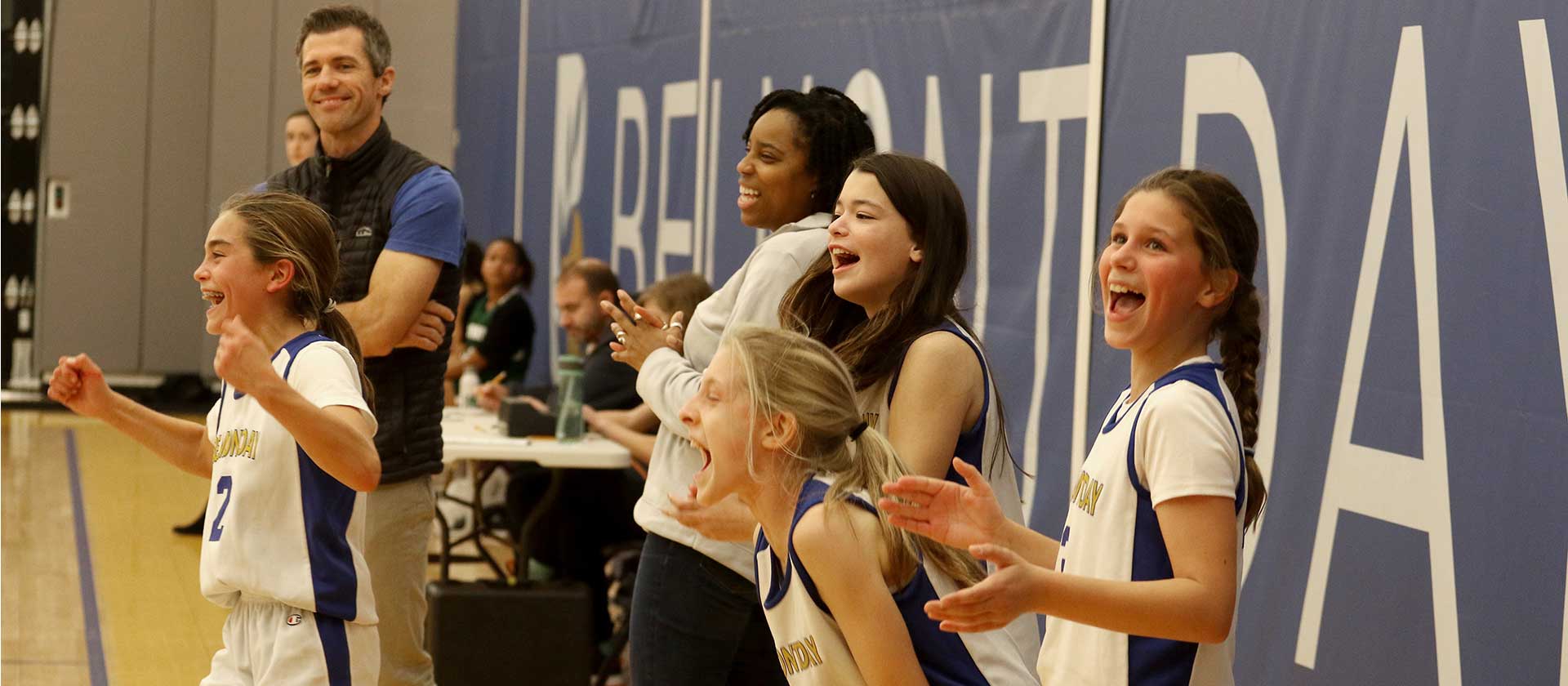 The girls basketball team and coaches celebrate a win