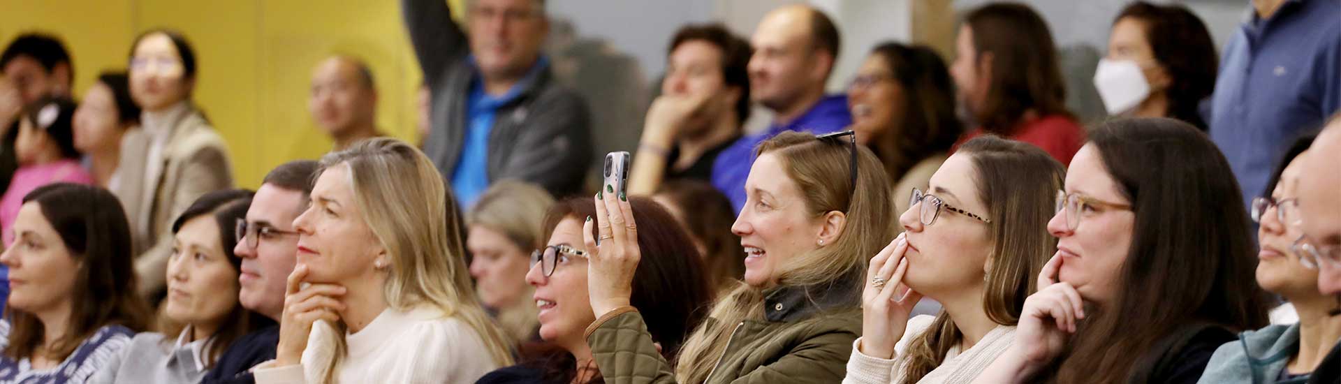 Parents smiling and snapping photos during sharing assembly