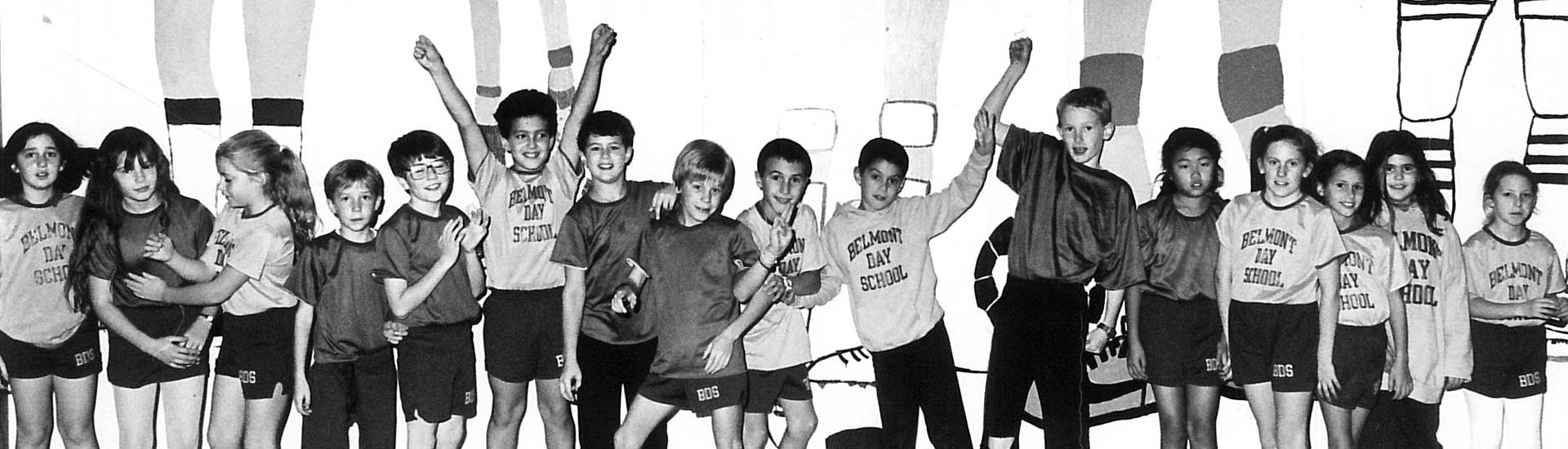 A black and white archival photos of students wearing Belmont Day School shirts and cheering on field day.