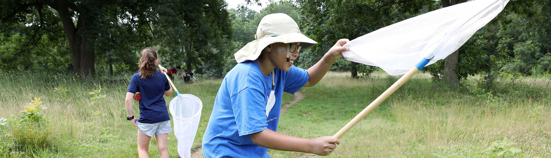 A STEM Nature Camp partipant in the meadow with an insect net