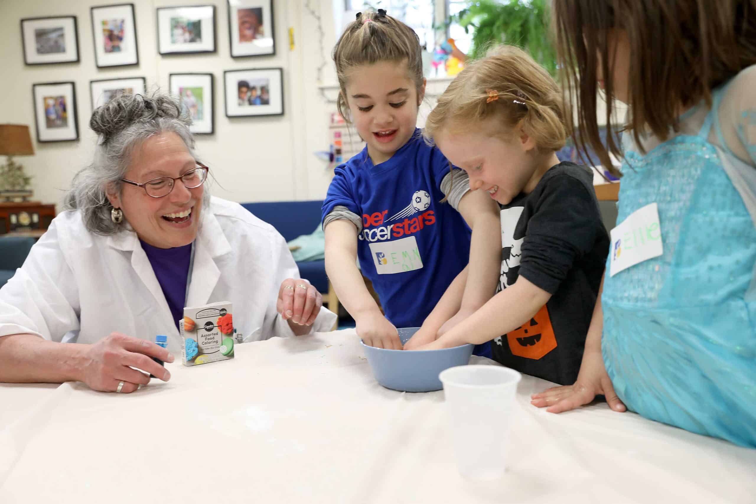A "mad scientist" leads an activity with two campers at April vacation camp