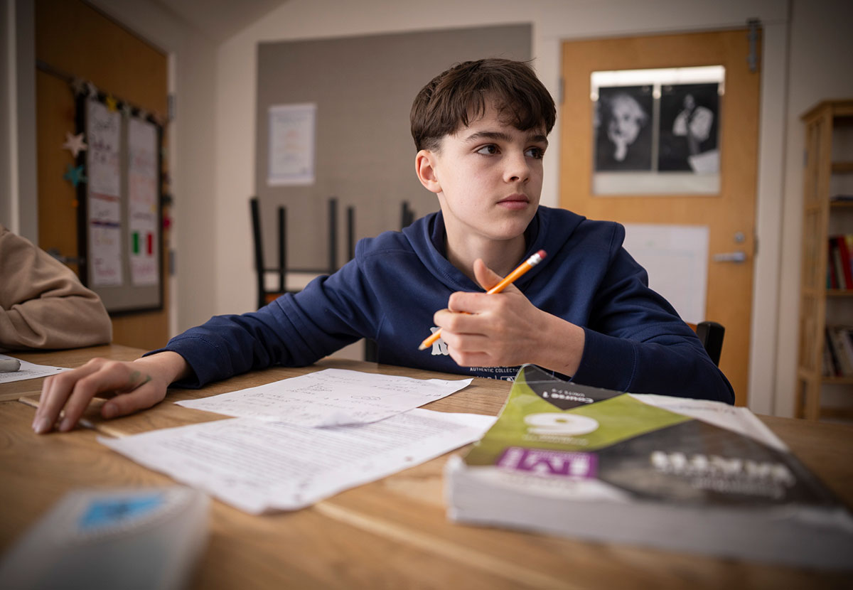 A student at a desk holding a pencil with a math textbook