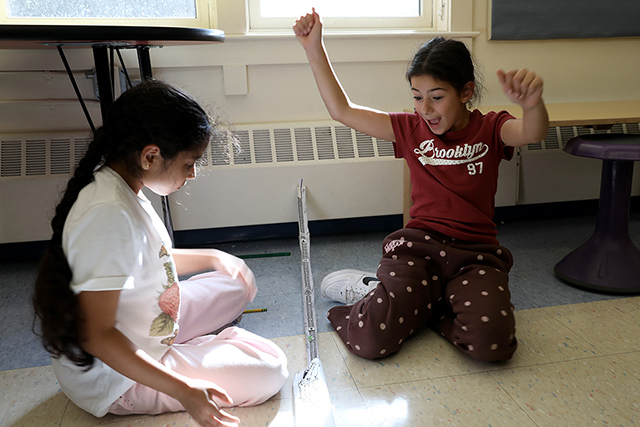 Two students set up a marble run in science class